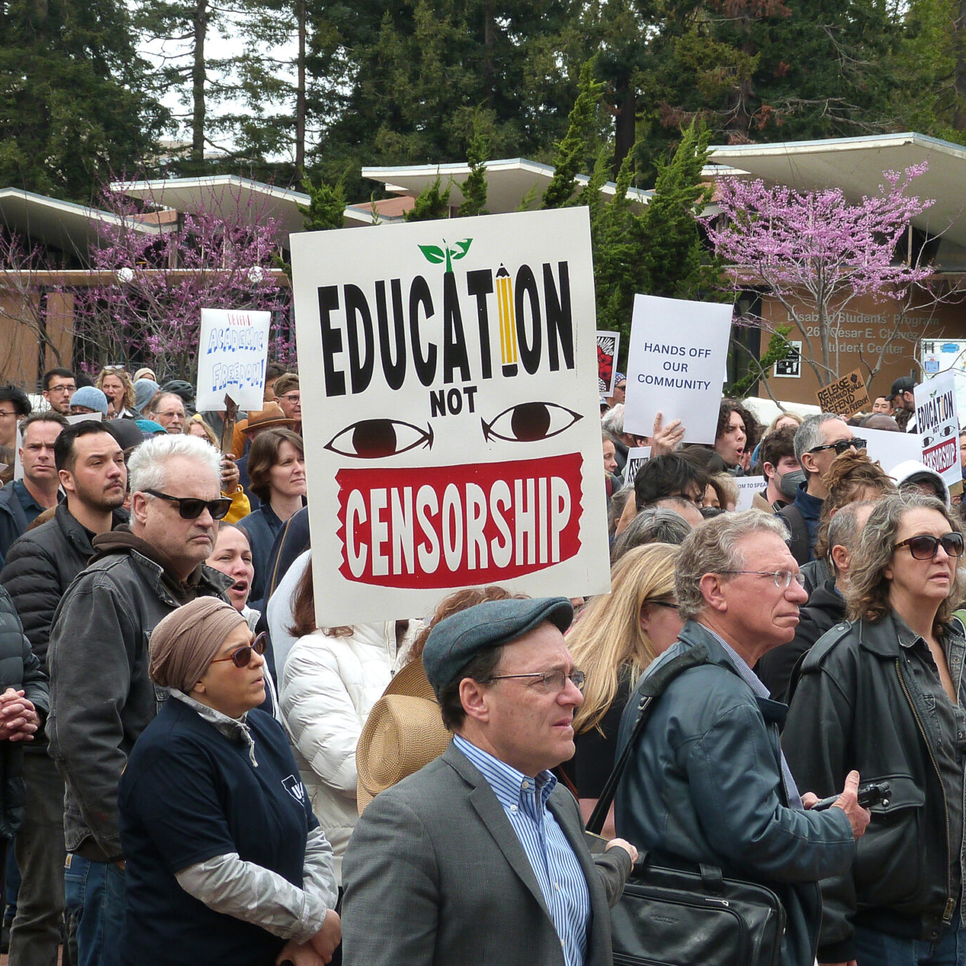A group of people at a protest, where a prominent sign says "Education not Censorship."
