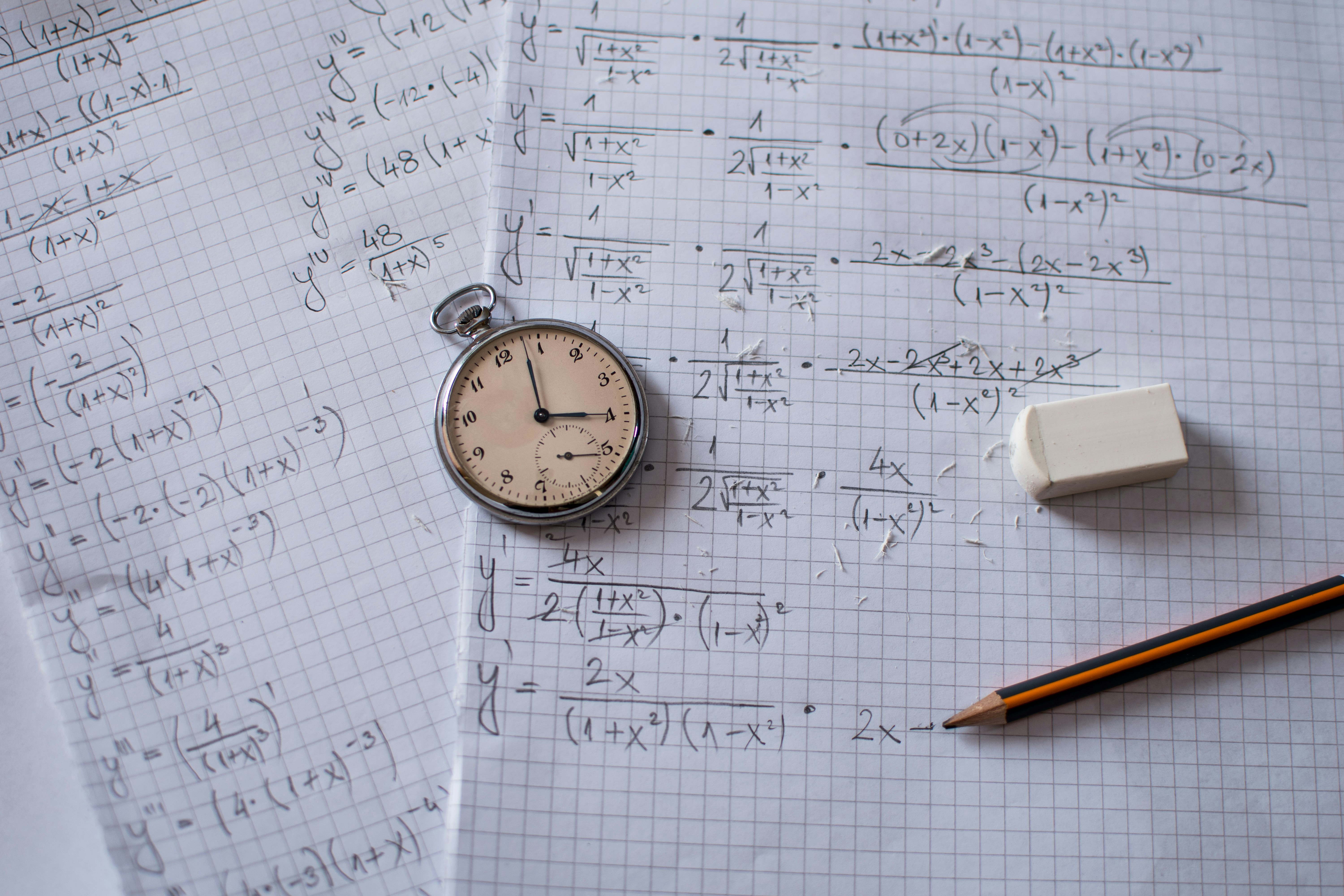 Calculus homework written on paper with a pencil, eraser, and pocketwatch laying on top.
